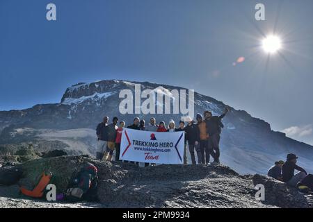 Un gruppo di escursionisti in piedi insieme su un picco di montagna che detiene la bandiera della squadra escursionistica Foto Stock