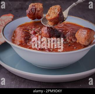 Ciotola di salsiccia casseruola guarnita con condimento. Foto Stock