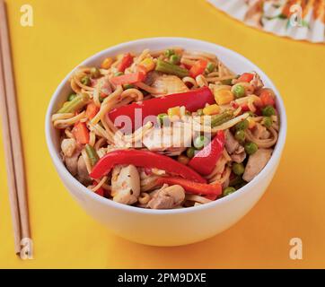 Ciotola di pollo dolce e asino con alcuni bastoncini di pollo su uno sfondo vivace. Foto Stock