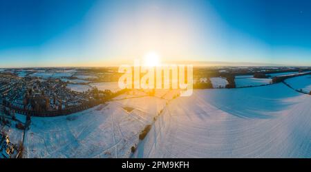 Paesaggio panoramico che guarda verso Cirencester nelle cotswolds all'alba con la neve. Cucito da più fotografie. Foto Stock