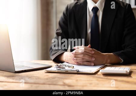 I lavoratori di prestito della banca stanno usando i calcolatori per calcolare i tassi di interesse di prestito domestico affinchè i clienti valuti le loro capacità di investimento usando il documento chiave Foto Stock