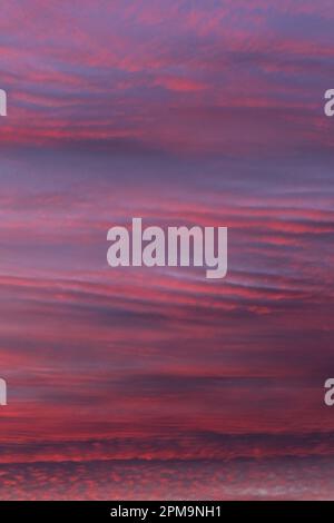 Tramonto in autunno producendo colori profondi nelle nuvole, mentre il sole cala sotto l'orizzonte. Foto Stock