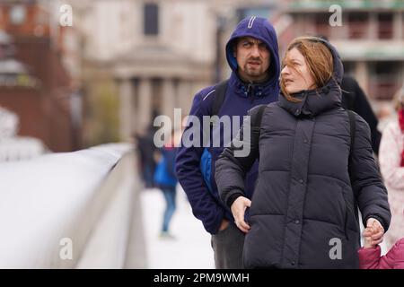 La gente cammina attraverso il Millennium Bridge, Londra, mentre i venti forti si muovono attraverso la capitale. Data immagine: Mercoledì 12 aprile 2023. Foto Stock