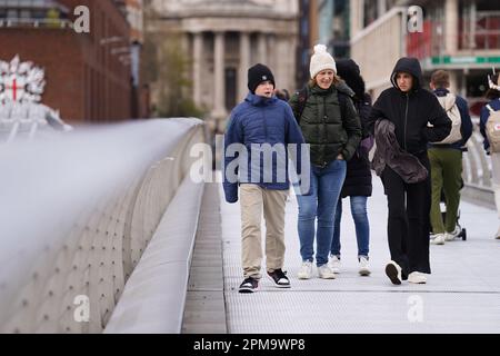 La gente cammina attraverso il Millennium Bridge, Londra, mentre i venti forti si muovono attraverso la capitale. Data immagine: Mercoledì 12 aprile 2023. Foto Stock