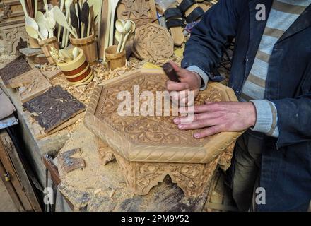 Fez, Marocco - 07 gennaio 2020: Uomo sconosciuto nella sua lavorazione del legno o scultura officina vicino al mercato di strada. molti souvenir di legno e prodotti intorno a lui Foto Stock