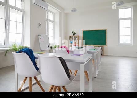 Interno della scuola moderna con scrivanie, sedie, lavagna e lavagna bianca Foto Stock