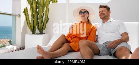 vacanza romantica. coppia sorridente che si rilassa nel lettino insieme sulla terrazza dell'attico e che si gode le vacanze estive Foto Stock