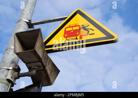 Altoparlante di annuncio e segnale di avvertimento giallo triangolare per i passeggeri su una piattaforma tedesca che significa attenzione ai treni in arrivo e in transito Foto Stock