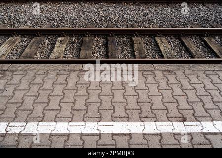 Piattaforma ferroviaria con pietre di pavimentazione e binari ferroviari Foto Stock