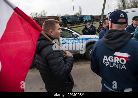 Hrubieszow, Polonia. 12th Apr, 2023. Gli agricoltori che protestano stanno guardando un treno che passa che trasporta grano ucraino alla linea ferroviaria a scartamento largo che attraversa la città di confine di Hrubieszow. La polizia ha impedito l'annunciata protesta di mercoledì mattina degli agricoltori dell'organizzazione AgroUnia (AgroUnion) guidata da Michal Kolodziejczak, che si suppone blocchino la linea ferroviaria a scartamento largo nella città di confine di Hrubieszow, dove il grano proveniente dall'Ucraina entra in Polonia. Come ha detto Michal Kolodziejczak, la protesta è stata denunciata per 7 giorni, ma gli agricoltori sono pronti a prolungarla. Credit: SOPA Images Limited/Alamy Live News Foto Stock