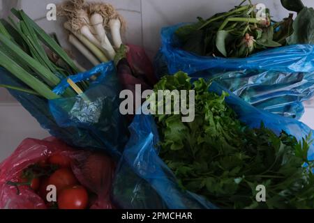 Shopping di verdure, sacchetti di plastica con verdure fresche diverse sul banco bianco in cucina. Foto Stock