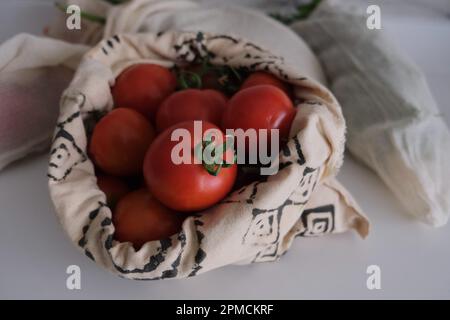 Shopping sano drogheria, pomodori verdure in borsa eco-friendly sul piano della cucina. Foto Stock