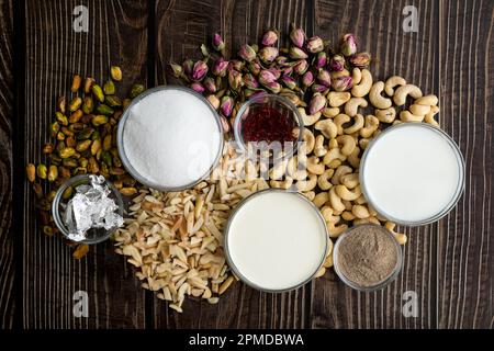 RAS Malai Mousse ingredienti su un tavolo di legno: Crema, zucchero, zafferano, e altri ingredienti per preparare e guarnire un dolce indiano fusion dessert Foto Stock