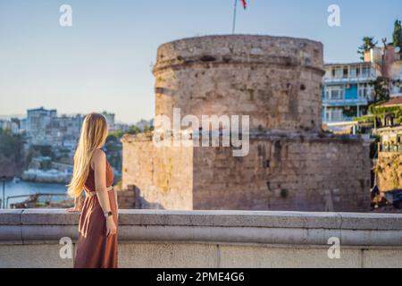 Donna turistica sullo sfondo della Torre Hidirlik di Antalya sullo sfondo della baia mediterranea dell'antico quartiere di Kaleici, Turchia Foto Stock