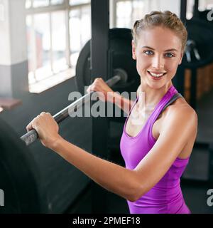 È un buon giorno per sollevare qualcosa di pesante. una giovane donna che si allenava con i pesi in palestra. Foto Stock