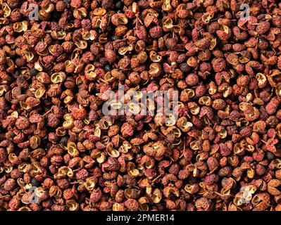 Pepe di Sichuan messo in tutto lo schermo. Il pepe di Sichuan è un membro della famiglia del sansho usato nella cucina cinese. Vista direttamente dall'alto. Foto Stock