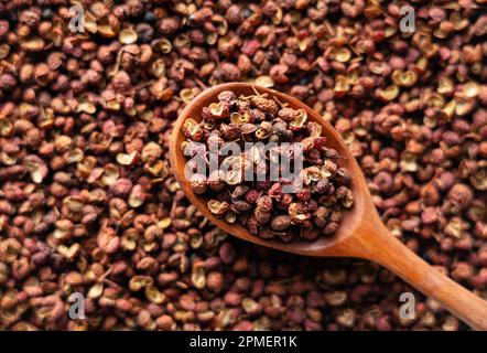 Pepe di Sichuan e cucchiai di legno messi in tutto lo schermo. Il pepe di Sichuan è un membro della famiglia del sansho usato nella cucina cinese. Vista da di Foto Stock