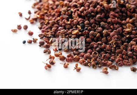 Pepe di Sichuan posto su uno sfondo bianco. Il pepe di Sichuan è un membro della famiglia del sansho usato nella cucina cinese. Foto Stock