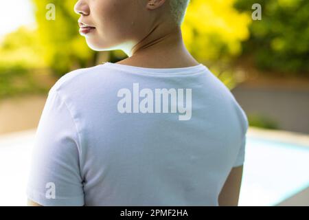 Primo piano di una donna biraciale che indossa una maglietta bianca sulla piscina in giardino Foto Stock