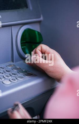 Stretta di mano immettendo il PIN presso un bancomat. Donna che utilizza la macchina bancario. Foto Stock