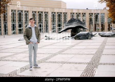 Ritratto di uomo attraente con abiti casual a piedi in Europa. un ragazzo in giacca si trova sulla strada durante la stagione autunnale. Ritratto OH bello teen Foto Stock