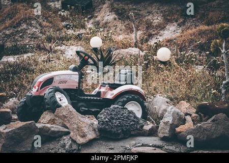 Trattore giocattolo rotto abbandonato in collina Foto Stock