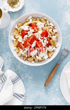 Dakos o insalata di koukouvagia. Ricetta classica insalata di fette biscottate di orzo cretese con pomodoro fresco, mizithra e origano. Tradizionale greco mediterraneo cu Foto Stock