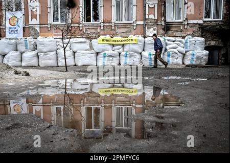 ORIKHIV, UCRAINA - 12 APRILE 2023 - Un uomo anziano passa accanto a sacchi di sabbia sigillando un punto di invincibilità, Orikhiv, Zaporizhzhzhzhia Regione, sud-est Foto Stock