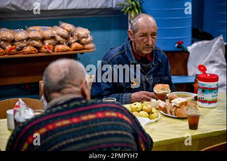 ORIKHIV, UCRAINA - 12 APRILE 2023 - Un uomo mangia in un punto di invincibilità, Orikhiv, Zaporizhzhzhia Regione, sud-est Ucraina. Foto Stock