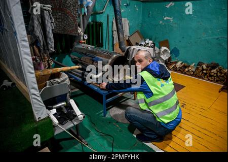 ORIKHIV, UCRAINA - 12 APRILE 2023 - Un uomo si siede sulle sue fienili da una stufa in un punto di invincibilità, Orikhiv, Zaporizhzhzhia Regione, Ukra sud-orientale Foto Stock