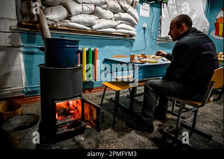 ORIKHIV, UCRAINA - 12 APRILE 2023 - Un uomo mangia in un punto di invincibilità da una stufa, Orikhiv, Zaporizhzhzhzhia Regione, sud-est Ucraina. Foto Stock