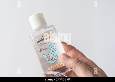 Mano femmina che contiene un flacone di gel igienizzante per le mani. Foto Stock