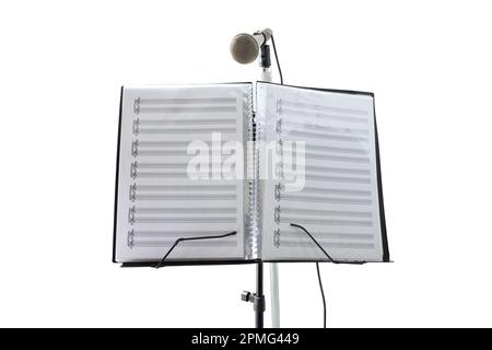 Supporto per musica vocale con spartiti musicali e microfono in un'ampia e luminosa sala interna con luci dorate. Vista frontale Foto Stock