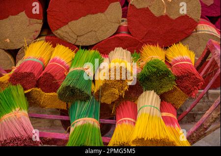 Alto angolo di pile di incenso colorati bastoni legati con nastri collocati su carrello di metallo rosa in produzione in Vietnam Foto Stock