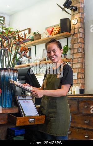 Cameriera felice vietnamita che lavora in una cucina di un caffè Foto Stock