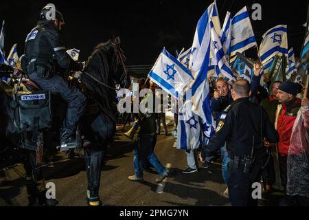 Hadera, Israele. 12th Apr, 2023. I manifestanti anti anti delle riforme cantano e agitano le bandiere israeliane accanto a un cavallo di polizia durante la manifestazione. I manifestanti pro e anti della riforma giudiziaria ad Hadera, dimostrano al di fuori di una cerimonia Mimouna in partecipazione del primo ministro Benjamin Netanyahu, si sono verificati scontri tra i manifestanti anti anti anti anti-riforma e gli attivisti di destra favorevoli alla riforma. Credit: SOPA Images Limited/Alamy Live News Foto Stock