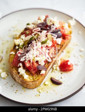 Dakos insalata tradizionale greca insalata con fette biscottate di orzo o pane ammollato e croccante, condita con pomodori succosi, formaggio feta, cipolle, olive, e un Foto Stock