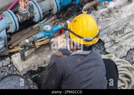 Un addetto alla manutenzione controlla i tubi dell'acqua in un edificio di appartamenti Foto Stock