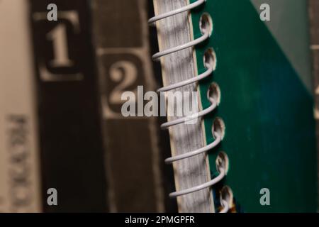 Un notebook caricato a molla tra i vecchi volumi di libri marroni, vista macro in primo piano Foto Stock