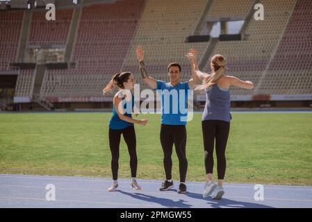 Felice sportivo maschile dando alti cinque ai suoi amici femminili Foto Stock