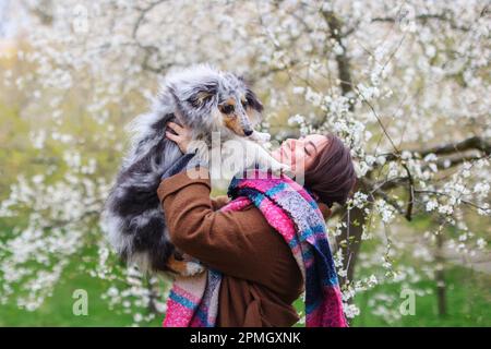 Gli uomini imparano il suo cane sheltie nel giardino primaverile Petrin a Praga Foto Stock