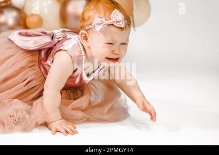 La bambina rossa piangente poco infelice celebra il primo anniversario di compleanno. Festa di famiglia di 1 anni Fotografia professionale in studio fotografico. adora carino Foto Stock