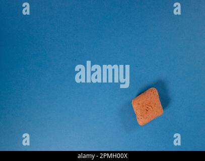 biscotto singolo a forma di diamante isolato su sfondo blu Foto Stock