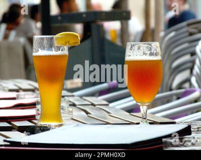 birra e bicchieri di birra con schiuma sul tavolo del ristorante bevanda color ambra dorato. caldo giorno d'estate. ristorante e pub scena sfondo morbido. persone. Foto Stock