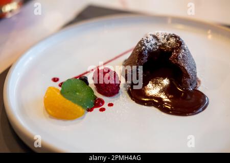 Lava al cioccolato su piatto, con frutta e salsa Foto Stock