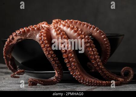 Fotografia a basso tasto del polpo bollito nel piatto, spazio per il testo Foto Stock