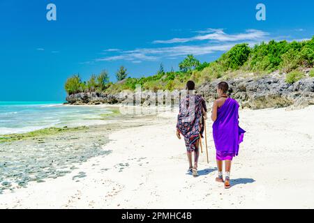 Bella donna Maasai con uomo che cammina sulla spiaggia vuota, Zanzibar, Tanzania, Africa orientale, Africa Foto Stock