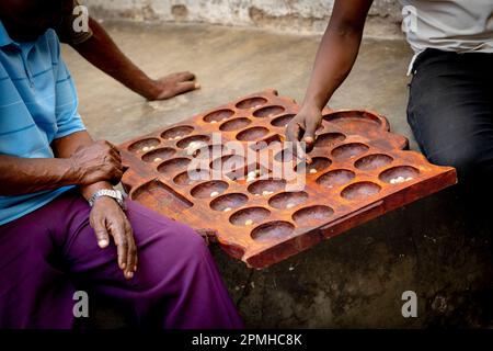 Uomini che giocano il famoso gioco da tavolo Bao in strada, Stone Town, Zanzibar, Tanzania, Africa orientale, Africa Foto Stock