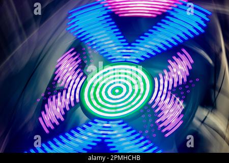 Le luci colorate di un carnevale in rapido movimento sfocano in movimento per formare una texture interessante e un elemento grafico di sfondo per i designer. Foto Stock
