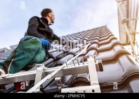 Installazione del sistema di montaggio per pannelli solari su un tetto a tegole Foto Stock